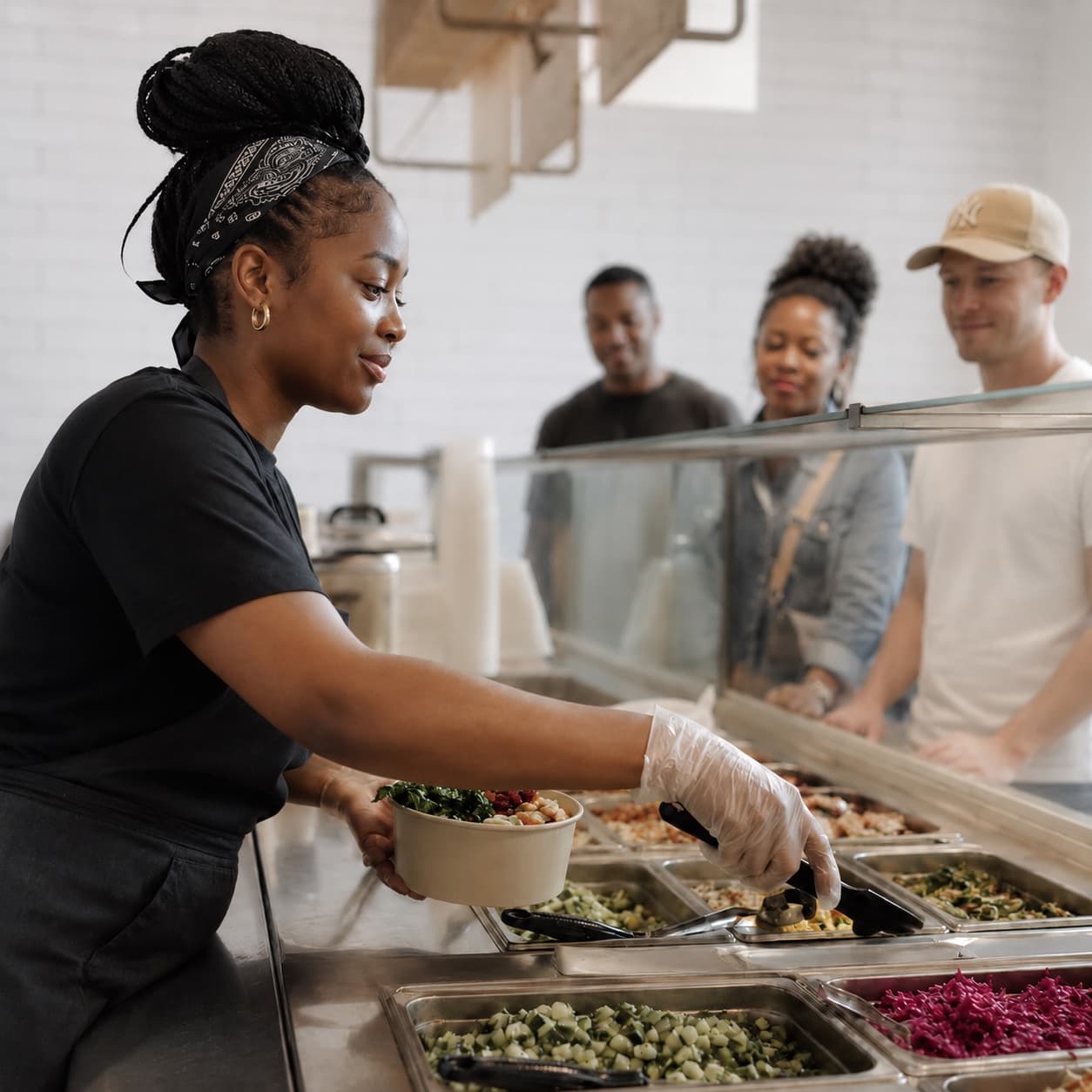 A stall server handing a fresh bowl across the counter to waiting customers