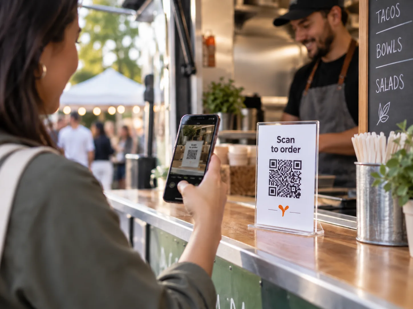 A customer scanning the Scan to order code on a food truck counter while the trader serves